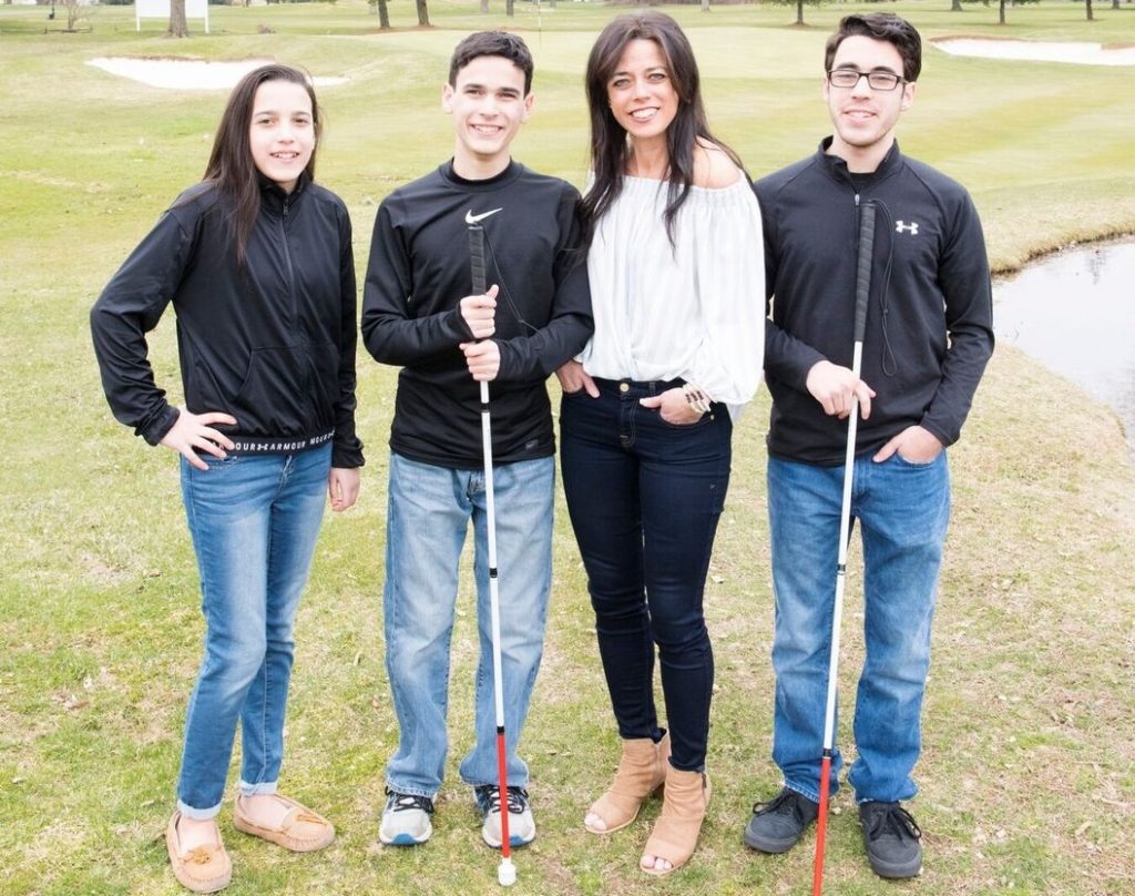 Kristin and her hildren standing on grass. Both boys are holding their canes