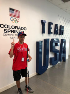 Mitchellinfront of the  Oympic Training Center  Logo and TEAM USA  onthe wall b ehind him.
