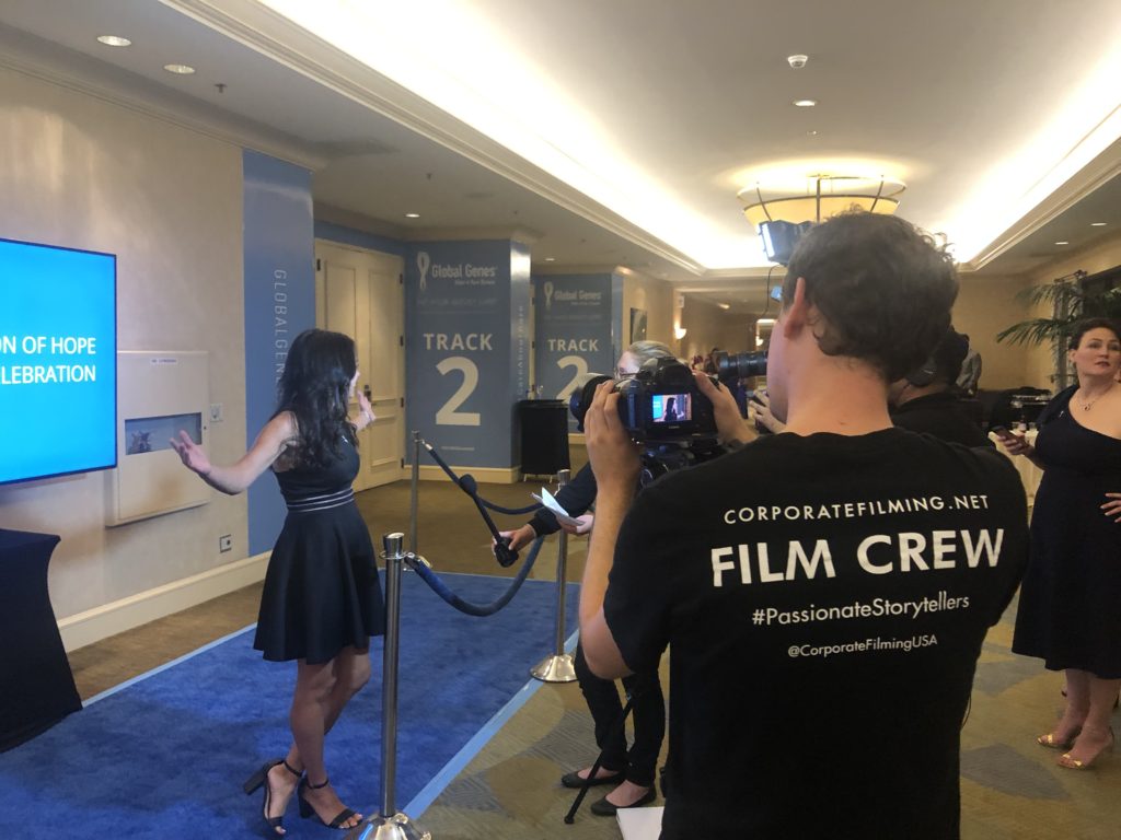 Kristin speaking to a film crew standing on a fancy blue carpet