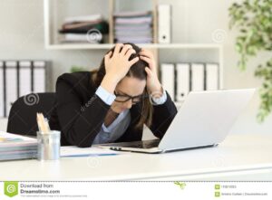 office worker holding her head in frustration while in front of her laptop